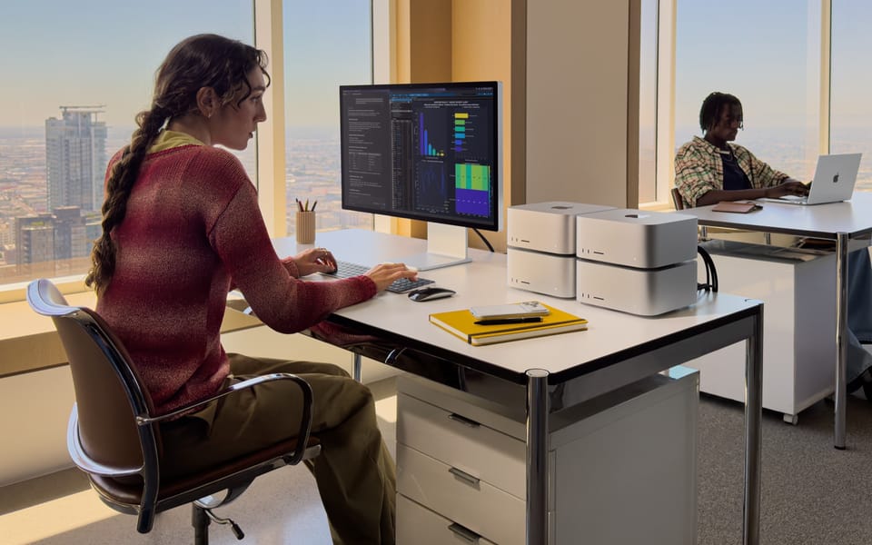 Office workers at desks using a Mac Studio with a display and a MacBook