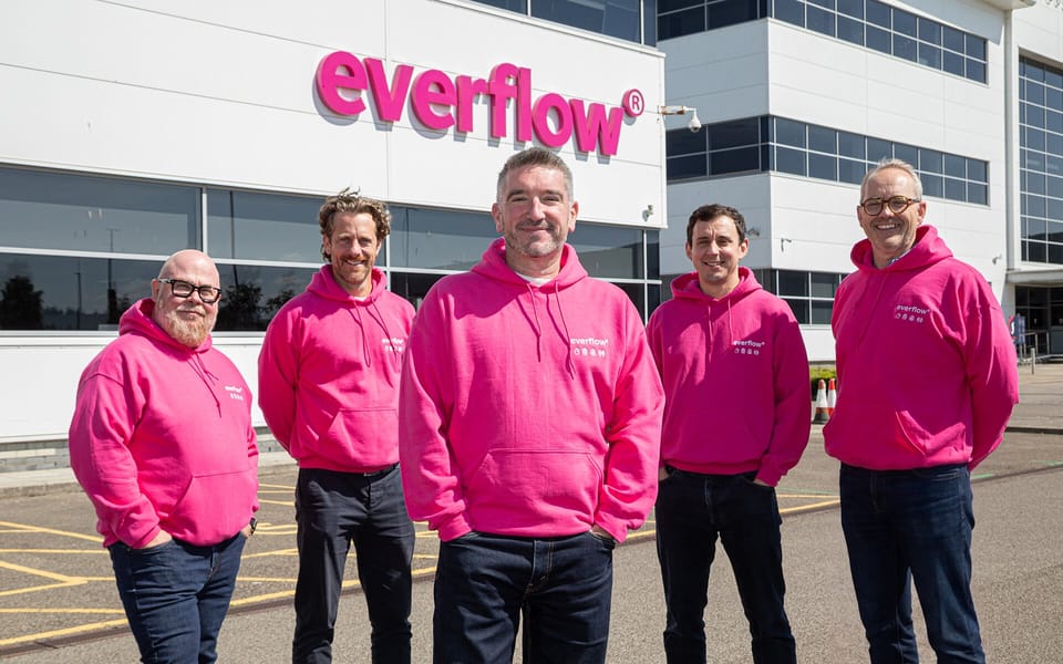 Five people in pink Everflow hoodies outside Everflow’s offices