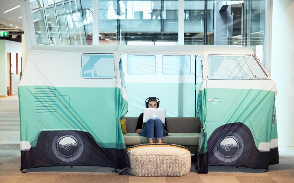 A woman wearing headphones works on a laptop inside a camper-van-shaped tent in Meta's London office