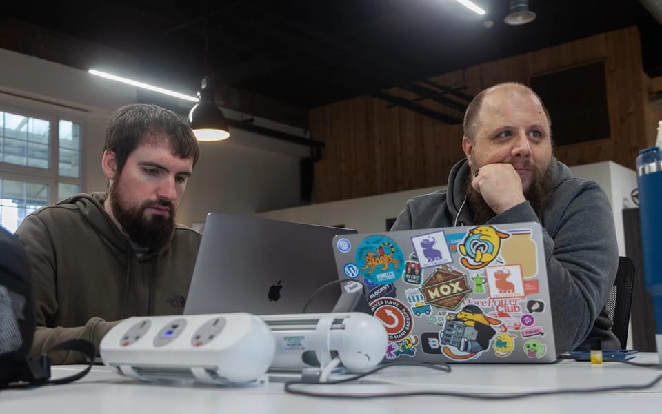 Two TeamUpdraft staff working on laptops at a shared desk