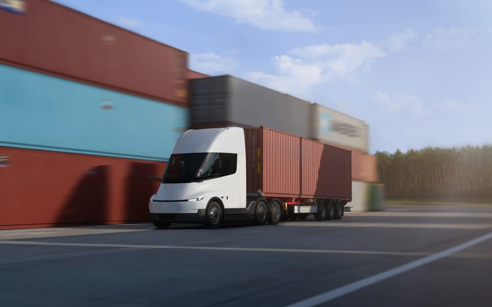 Tesla Semi electric truck hauling a shipping container past stacked containers