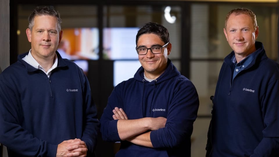 Outerlimit's three co-founders, Tony Pepper, Neil Larkins and Peter Vincent, standing in an office in navy Outerlimit-branded tops