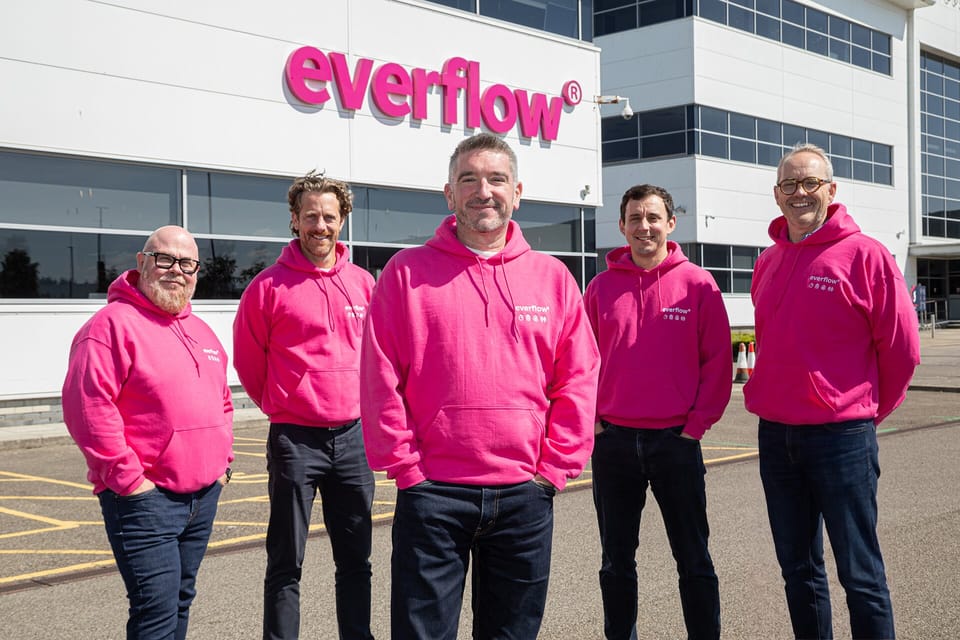 Five people in pink Everflow hoodies outside Everflow’s offices