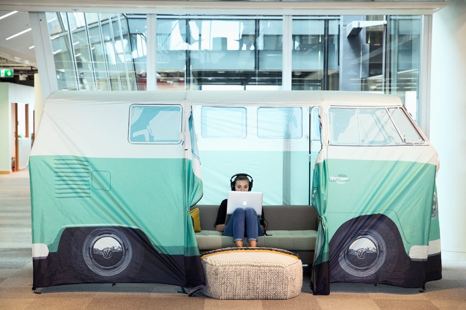 A woman wearing headphones works on a laptop inside a camper-van-shaped tent in Meta's London office