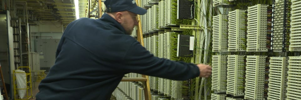An Openreach engineer working on copper line frames inside a telephone exchange