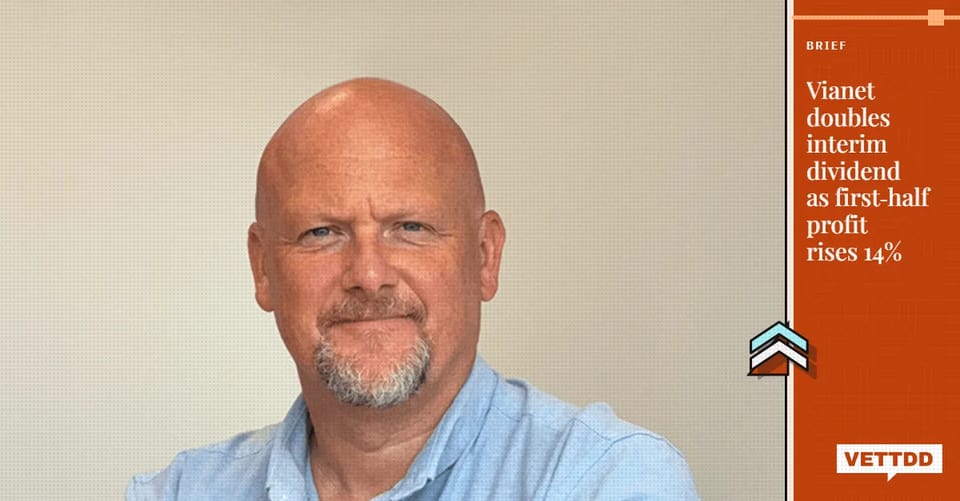 Craig Brocklehurst, chief executive of Vianet Group, with a burnt orange VETTDD banner reading 'Vianet doubles interim dividend as first-half profit rises 14%'