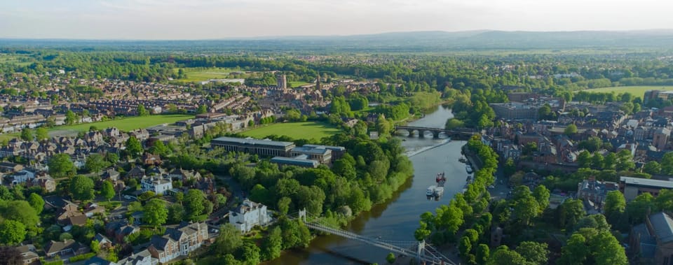 Aerial view of a riverside town with a suspension bridge and surrounding countryside