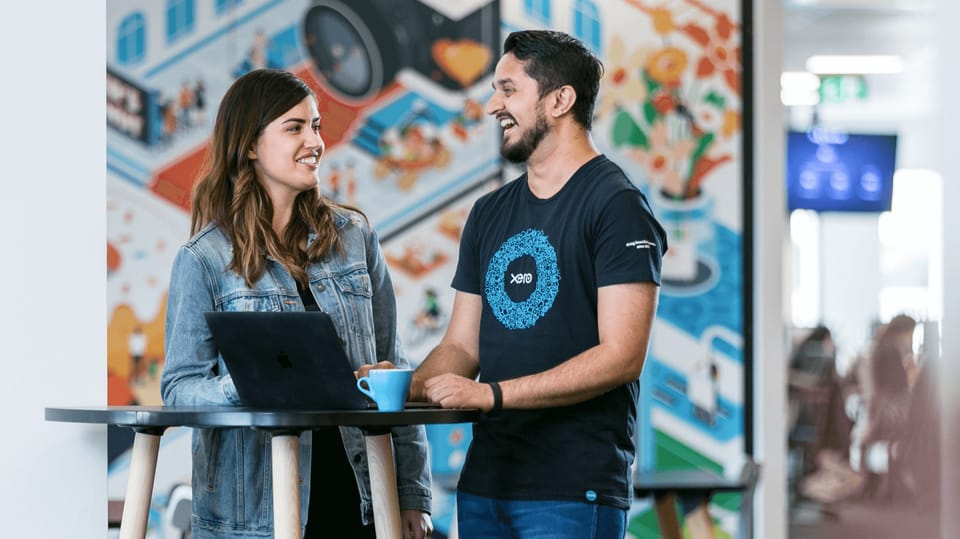 Two Xero colleagues talking at a laptop in a Xero office